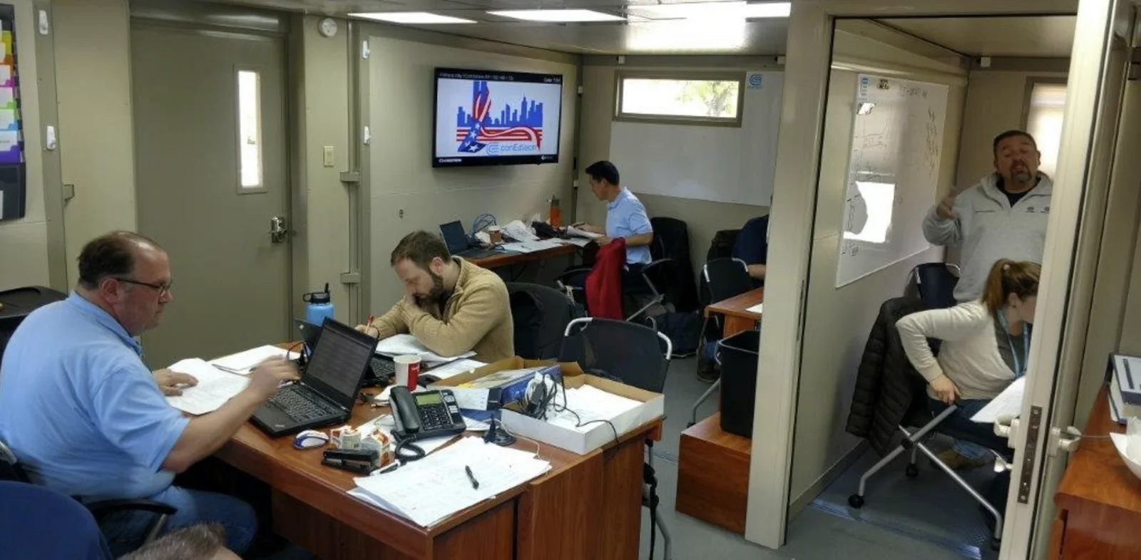 Team working at desks inside a FORTS command center, with computers, phones and a partitioned work area