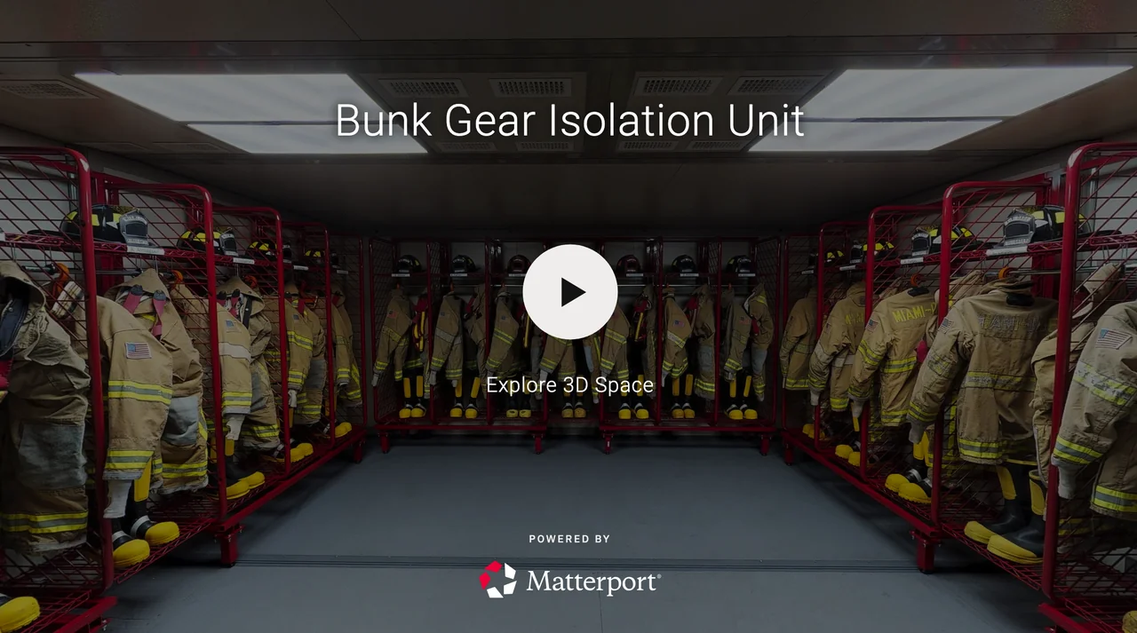 Firefighter gear including jackets, helmets, boots, and masks organized on red metal storage racks in a room, with the text 'Bunk Gear Isolation Unit' and a play button overlay.