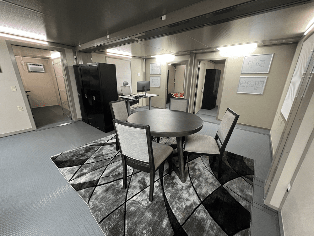 Fire-station interior with shared table, lockers and a desk workspace